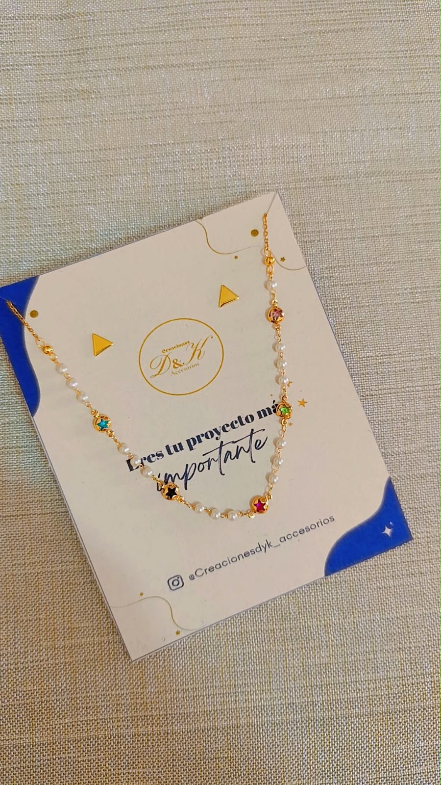 Choker de perla y estrellas multicolor en cadena dorada sobre tarjeta de presentación